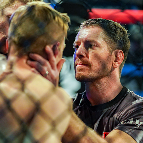 Brandt standing with a boxer, offering grounded support and guidance during an intense training moment.